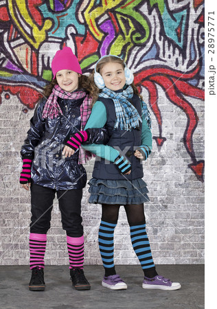 Girls in front of the wall covered with graffiti Girls in front of the wall covered with graffiti 28975771