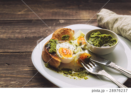 Boiled egg with toasted bread and pesto sauce 28976237
