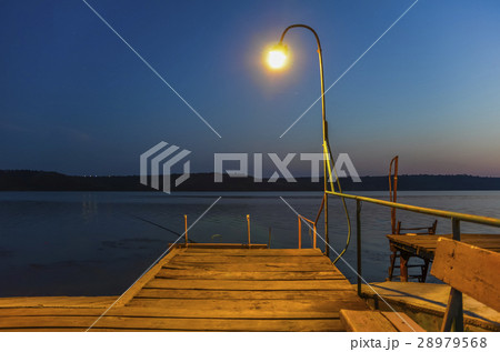 Wooden pier on the lake lit by lamp. Wooden pier on the lake lit by lamp. 28979568