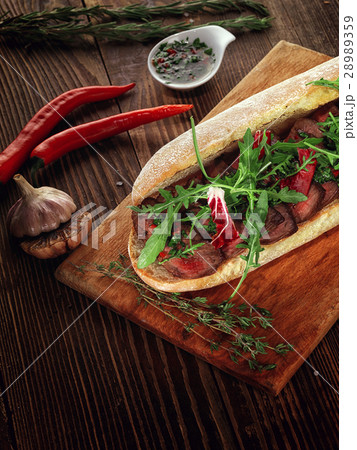 Sandwich with beef steak on a wooden stand. Sandwich with beef steak on a wooden stand. 28989359