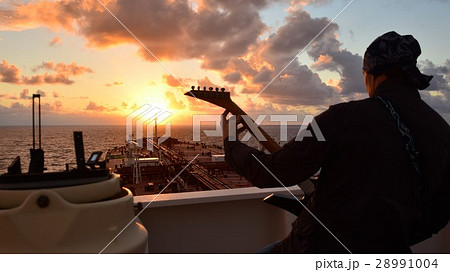 A man playing guitar and singing at sunset on boar 28991004