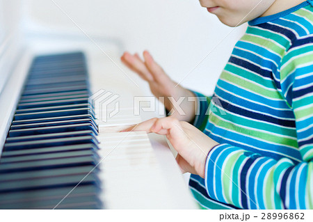 Beautiful little kid boy playing piano in living Beautiful little kid boy playing piano in living 28996862