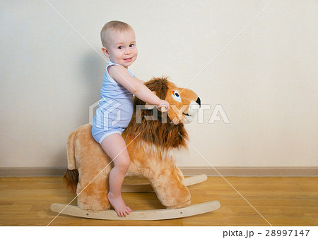 Cute small baby boy riding on the lion toy . Happy Cute small baby boy riding on the lion toy . Happy 28997147