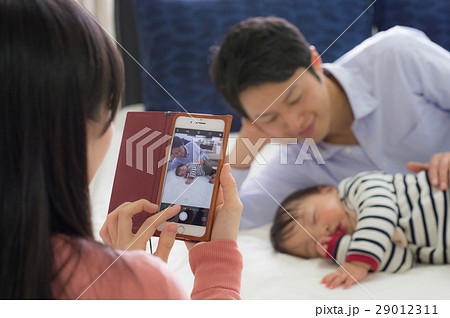 添い寝する父子とスマホ撮影する母 29012311