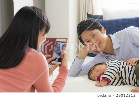 パパと赤ちゃんの寝顔をスマホ撮影するママ 29012313