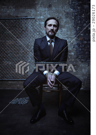Unimpressed businessman imprisoned somewhere dark Unimpressed businessman imprisoned somewhere dark 29026173