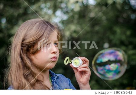 Portrait of cute little girl blowing soap bubbles. 29035642
