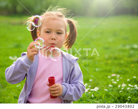 Little girl blows soap bubbles on meadow Little girl blows soap bubbles on meadow 29043802