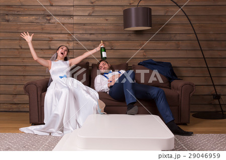 Drunk bride with bottle, groom sleeping on couch 29046959