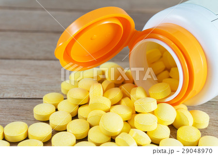 Yellow pills in plastic bottle on wood background Yellow pills in plastic bottle on wood background 29048970