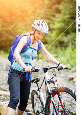 Young woman with bicycle wade the mountain creek 29055861