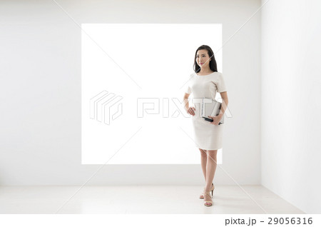 パネルの前にノートパソコンを持って立つ若い女性 パネルの前にノートパソコンを持って立つ若い女性 29056316