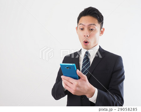 青いスマホを持って驚く若いビジネスマン 青いスマホを持って驚く若いビジネスマン 29058285