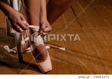 ballerina tying ballet shoes sitting on the stage 29063275