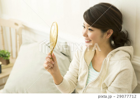 手鏡を見る笑顔の20代女性 29077712