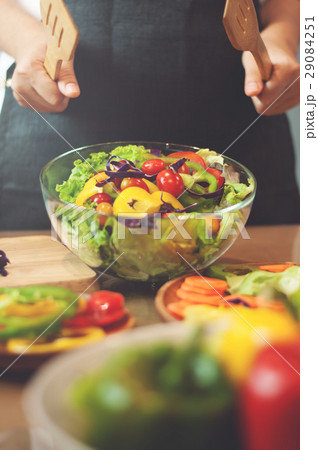 Woman cooking salad with vegetables. Woman cooking salad with vegetables. 29084251