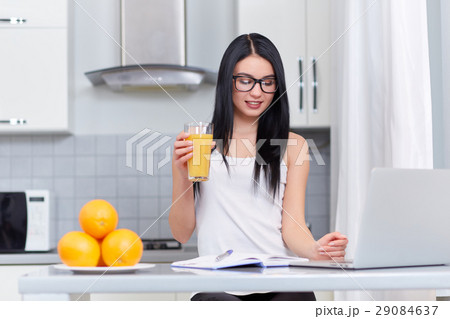 Girl in glasses writing home task at kitchen. Girl in glasses writing home task at kitchen. 29084637