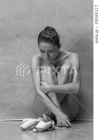 Tired ballet dancer sitting on the wooden floor on 29089127