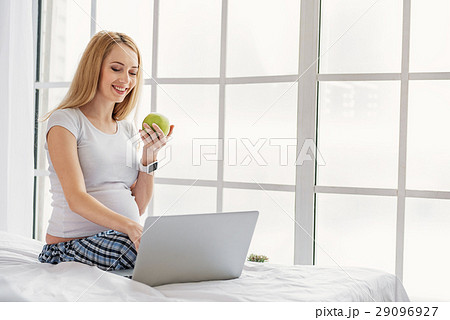 Smiling future mother using computer Smiling future mother using computer 29096927