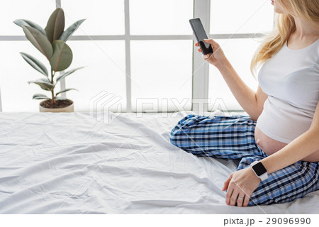 Beautiful future mother using mobile phone in her 29096990