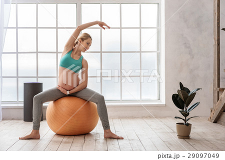Happy expectant female doing gymnastic at living 29097049