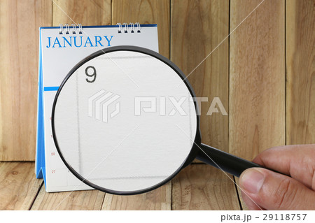 Magnifying glass in hand on calendar in January. 29118757