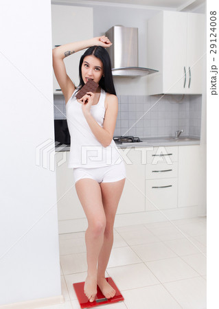 Woman in pajama weighting at kitchen and eating 29124008