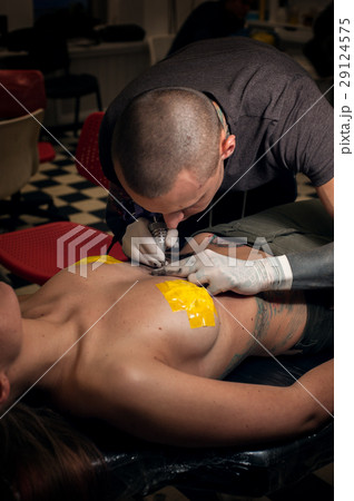 Tattooer wearing sterile gloves tattooing woman Tattooer wearing sterile gloves tattooing woman 29124575