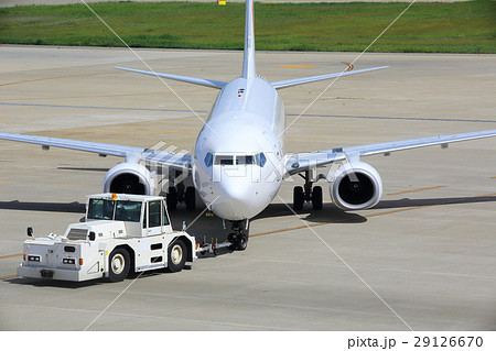 トーイングカーで牽引される飛行機の写真素材