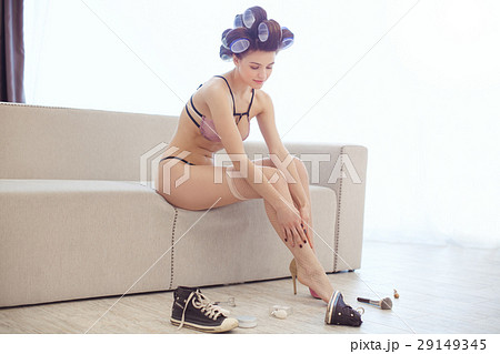 Woman dressing up in fishnet stockings indoors 29149345