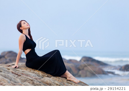 beautiful young woman sitting on the stone coast beautiful young woman sitting on the stone coast 29154221