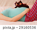 Young pregnant mother lies with soft toy of their future baby 29160536