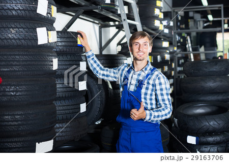 smiling mechanic man working with car tires in workshop 29163706
