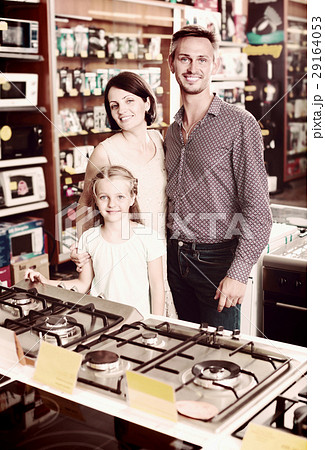 Smiling parents with daughter choosing new gas-stove Smiling parents with daughter choosing new gas-stove 29164053