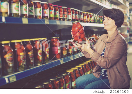 elderly woman buying canned tomatoes. 29164106