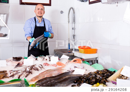 Old seller offering fresh fish 29164208