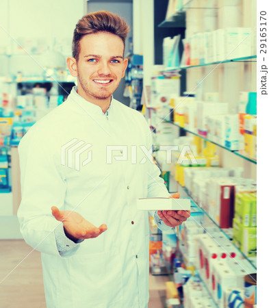 Ordinary man pharmacist standing among shelves 29165170