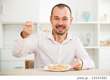 Positive young man eating porridge 29165882