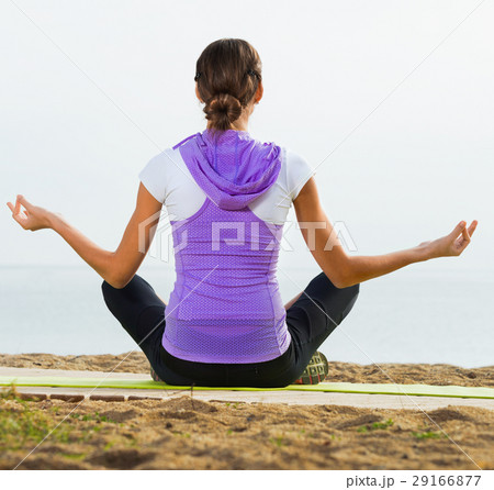 Woman doing youga training cross-legged on beach Woman doing youga training cross-legged on beach 29166877
