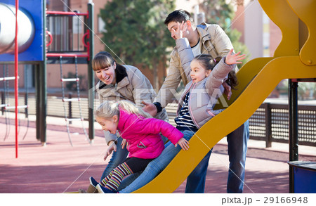 Cheerful family spending time at children slide Cheerful family spending time at children slide 29166948