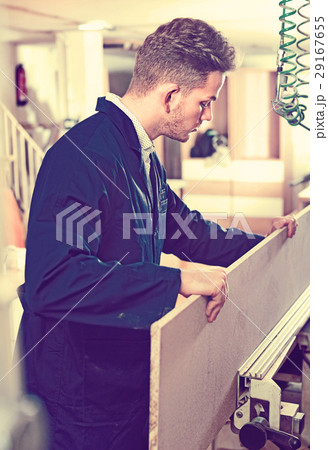Positive guy fixing chipboard on table at workshop 29167655