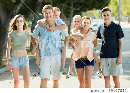 Large family of six people walking with kids on parents back in summer city 29167832