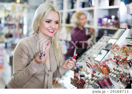 Positive female customer buying red lipstick in makeup section Positive female customer buying red lipstick in makeup section 29168713