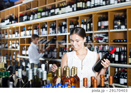 Young woman choosing bottle in wine shop Young woman choosing bottle in wine shop 29170403