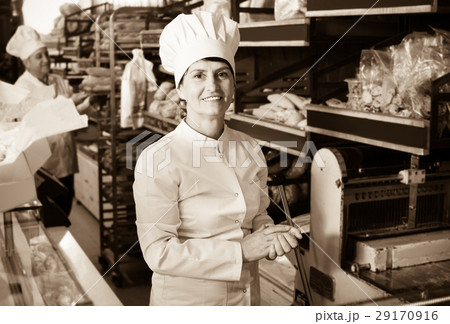 Bakery mature employee with tasty bread products Bakery mature employee with tasty bread products 29170916