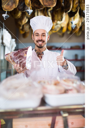 Male shop assistant demonstrating piece of meat in butcher’s shop 29173083