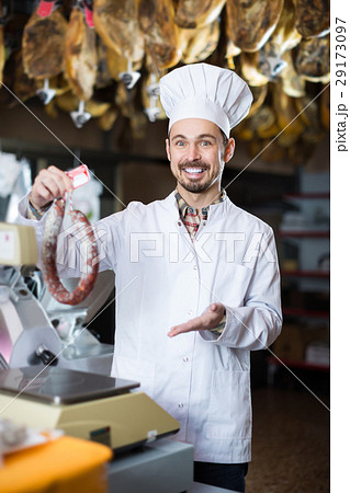 Smiling male seller weighing on scales sausage Smiling male seller weighing on scales sausage 29173097