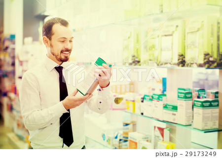 Smiling male customer browsing rows of drugs Smiling male customer browsing rows of drugs 29173249