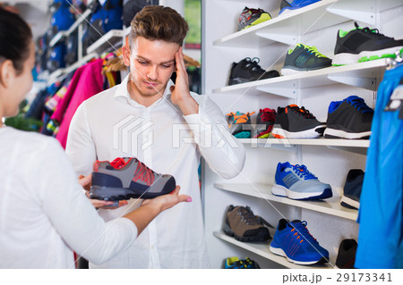 Couple examining various sneakers in sports store 29173341