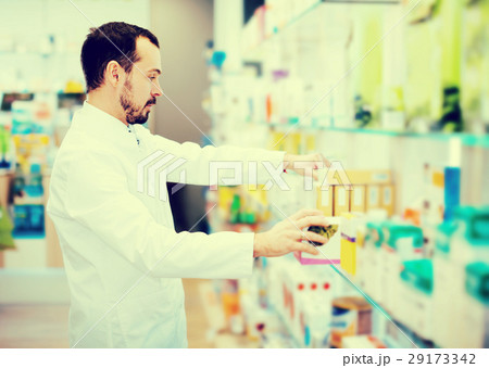 Male pharmacist searching for reliable drug 29173342